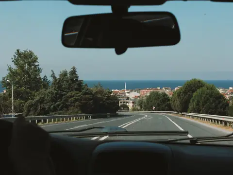 A highway seen through the windshield with the rear view mirror at the top